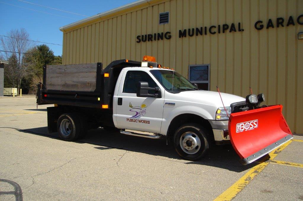 White Ford Super Duty F-350 dump truck features a prominent red snow plow mounted on the front