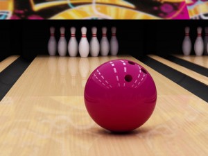 Pink bowling ball positioned on a wooden bowling lane
