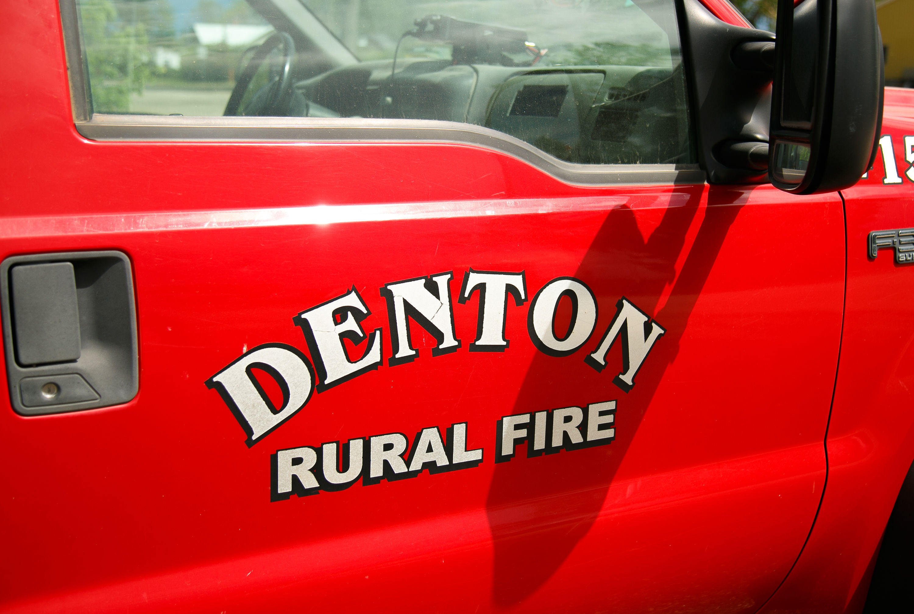 Close-up of a red fire truck door with text “DENTON FIRE RURAL FIRE.”