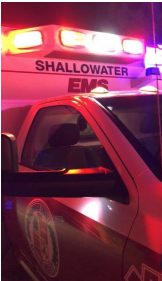Close-up of an ambulance with “SHALLOWATER EMS” text and flashing red and blue emergency lights.
