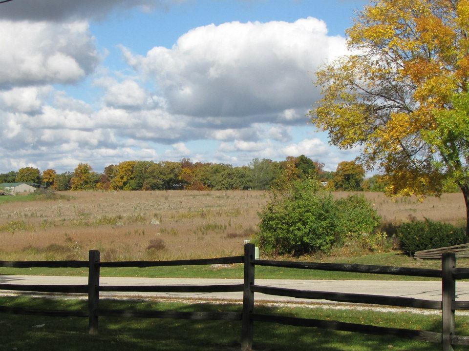 Wooden split-rail fence lining a field under an autumn sky